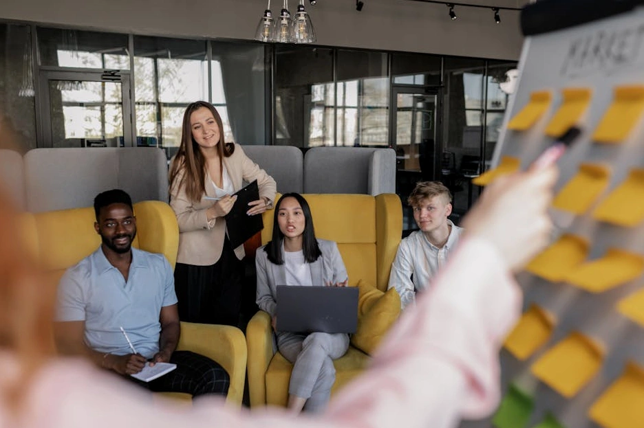 A diverse team of professionals collaborating around a table with charts and laptops.
